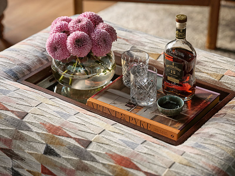 Luxurious custom-made ottoman with mirrored tray displaying flowers, coffee table book, and cocktail setup